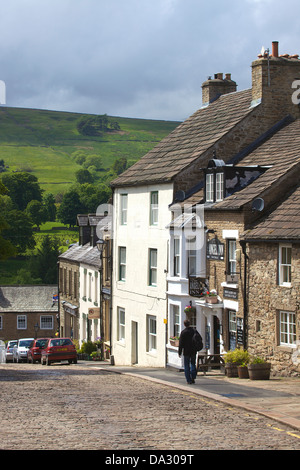 Uomo che cammina giù per la collina su Front Street Alston più elevati città in Inghilterra. Foto Stock