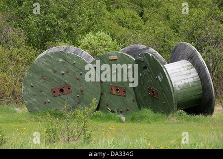 Tre vuoto industriale verde bobine artisticamente disposte sullo sfondo di verdi alberi Svartifoss Parco Nazionale di Islanda Foto Stock