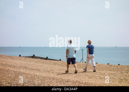 L uomo e la donna giovane camminando lungo la spiaggia su Hayling Island Hampshire Foto Stock