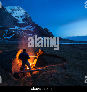 Due persone godono di falò in spiaggia Bunes, Moskenesoy, Isole Lofoten in Norvegia Foto Stock