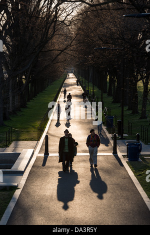 Il basso sole di mattina getta ombre lunghe da escursionisti lungo il nuovo marciapiede accanto al Lincoln Memorial riflettendo in piscina a Washington DC. Foto Stock