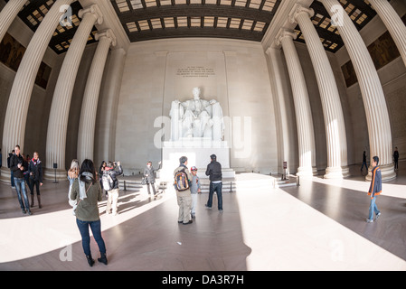 WASHINGTON DC, Stati Uniti: I visitatori si riuniscono intorno alla colossale statua di Abraham Lincoln di Daniel Chester French all'interno della camera commemorativa. La lente fisheye crea una spettacolare prospettiva curva della statua in marmo alta 19 metri e degli elementi architettonici circostanti. I turisti forniscono una scala alle enormi dimensioni interne del monumento. Foto Stock