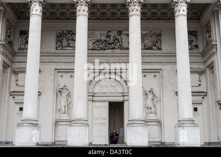 BRUXELLES, Belgio — l'ingresso neoclassico della Chiesa di Saint Jacques-sur-Coudenberg presenta un grande portico con colonne corinzie e fregi ornati. La chiesa, completata nel 1787, esemplifica lo stile architettonico formale che caratterizza Place Royale. La facciata classica mostra l'influenza neoclassica francese del XVIII secolo sull'architettura religiosa belga. Foto Stock