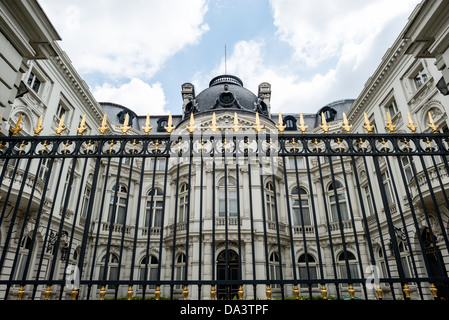 Recinto nero e dorato Quartiere Reale Bruxelles Belgio | BRUXELLES, Belgio — Capitelli dorati coronano una recinzione in ferro battuto nero davanti a un edificio con tetto a mansarda nel Quartiere Reale, un trattamento ornamentale caratteristico delle grandi strutture istituzionali e reali intorno al Coudenberg. Il Quartiere Reale, progettato alla fine del XVIII secolo intorno alla Place Royale, ha da tempo concentrato la corte, il governo e gli edifici culturali del Belgio in un distretto formale compatto. Foto Stock