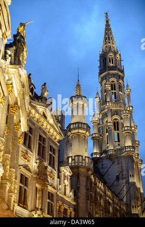 BRUXELLES, Belgio — a sinistra della cornice si trova una parte dell'esterno di una delle sale di gilda e a destra la torre del municipio nella Grand Place, Bruxelles. Originariamente la piazza del mercato centrale della città, la Grand-Place è ora un sito patrimonio dell'umanità dell'UNESCO. Gli edifici ornati fiancheggiano la piazza, tra cui le sale di gilda, il municipio di Bruxelles e la Breadhouse, e sette strade acciottolate vi si immettono. Foto Stock