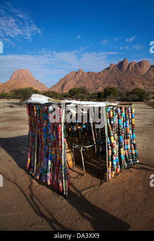 Capannone fatta di carta riciclata per lattine di bevande, Spitzkoppe e il Pondok montagne (a destra), Namibia, Africa Foto Stock