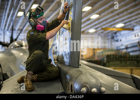 Cpl. Charles Gazaway, assegnato al Marine squadrone di attacco (VMA) 214, si applica il nastro prima di pittura stelle sulla verticale di pinna di coda Foto Stock