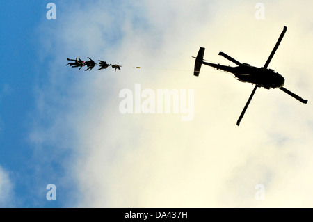 US Navy SEAL i membri del team a penzolare dalla speciale pattuglia di inserimento e di estrazione corda attaccata ad un UH-60 Black Hawk elicottero durante la formazione HELOCAST al Marine Corps Air Station Kaneohe Bay il 19 giugno 2013 nelle Hawaii. Foto Stock