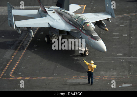 Un marinaio ci dirige un'F/A-18F Super Hornet fighter aircraft sul ponte di volo a bordo della portaerei USS Nimitz Luglio 1, 2013 operanti nel Golfo di Oman. Foto Stock