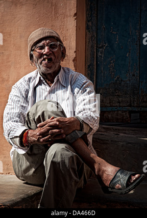 Un anziano uomo seduto su un passo di rimando. Jodhpur, Rajasthan, India Foto Stock