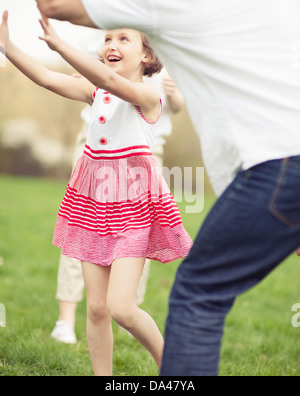 Padre madre e figlia lanciando la palla a vicenda nel parco Foto Stock