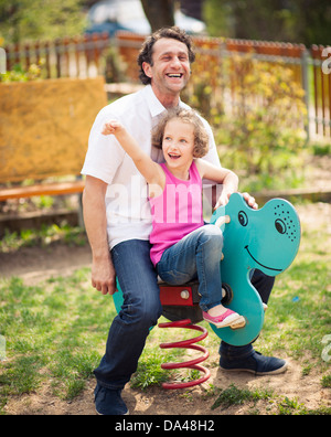 Padre e figlia sul parco giochi la molla pilota Foto Stock