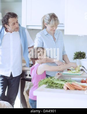 Famiglia facendo una sana insalata in cucina Foto Stock