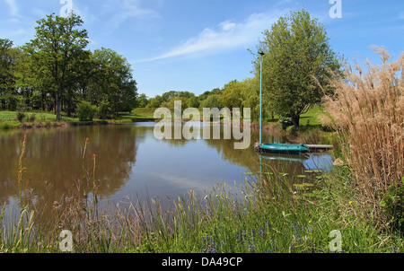 Tranquillo laghetto con una piccola barca al dock, Limousin Francia Foto Stock