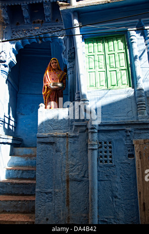 Donna in piedi al di fuori del dipinto di blu haveli residenziale. Jodhpur, Rajasthan, India Foto Stock