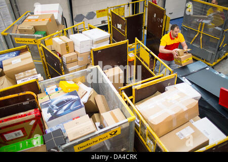 Un membro del personale della Deutsche Post DHL il servizio di spedizione pacchi posti su un nastro trasportatore alla recente apertura di spedizioni hub di DHL a Berlino, Germania, 3 luglio 2013. La struttura ha la capacità di elaborare fino a 8000 pacchetti e pacchi al giorno. Foto: Hannibal Hanschke Foto Stock