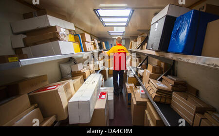 Un membro del personale della Deutsche Post DHL servizio di spedizioni di carichi di consegna il suo carrello con i pacchi presso il recentemente inaugurato la spedizione hub di DHL a Berlino, Germania, 3 luglio 2013. La struttura ha la capacità di elaborare fino a 8000 pacchetti e pacchi al giorno. Foto: Hannibal Hanschke Foto Stock