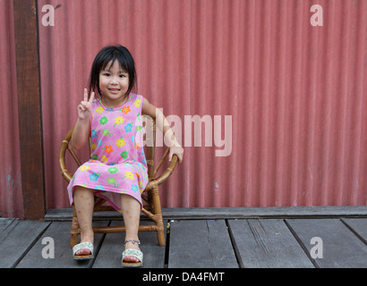 Bambina seduti sulla sedia sorridente clan di saldatura Quay Piers, Georgetown, Penang, Malaysia Foto Stock