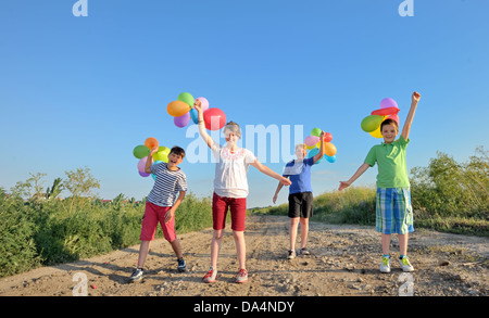 Felici i bambini con palloncini colorati in un campo Foto Stock