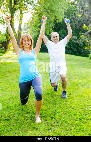 Femmina istruttore di fitness esercizio con uomo di mezza età in parco verde Foto Stock