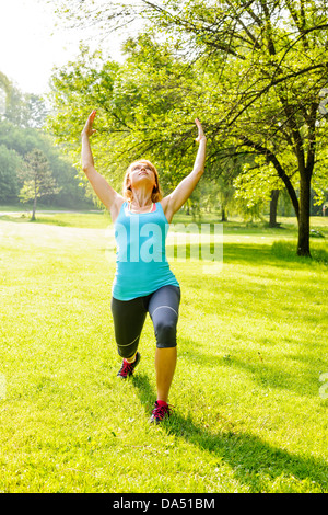 Femmina istruttore yoga in guerriero spirituale pongono al green park Foto Stock