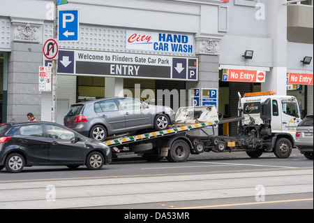 Un'auto viene trainata da un'area senza parcheggio in Flinders Street nel centro di Melbourne in quanto vengono applicate nuove leggi sul parcheggio. Foto Stock