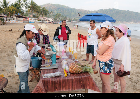 Persone locali vendono i succhi di frutta freschi sulla spiaggia, Guayabitos, Messico. Foto Stock