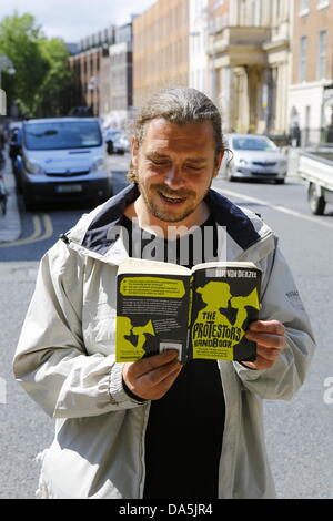 Dublino, Irlanda. 4 luglio 2013. Un manifestante sorge al di fuori del Dail e legge "protestor's Handbook" da Bibi van der Zee. I dimostranti si fermò in silenziosa al di fuori del Dail (parlamento irlandese), la lettura di libri, per mostrare i loro sentimenti verso i banchieri e la politica di austerità al parlamento. La protesta è stata ispirata dalla permanente movimento di persone che ha dato origine a Istanbul la piazza Taksim. Credito: Michael Debets/Alamy Live News Foto Stock