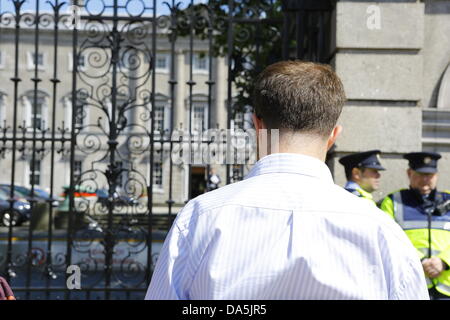 Dublino, Irlanda. 4 luglio 2013. Un manifestante sta in silenzio al di fuori del Dail. Il Dail può essere visto in background. I dimostranti si fermò in silenziosa al di fuori del Dail (parlamento irlandese), la lettura di libri, per mostrare i loro sentimenti verso i banchieri e la politica di austerità al parlamento. La protesta è stata ispirata dalla permanente movimento di persone che ha dato origine a Istanbul la piazza Taksim. Credito: Michael Debets/Alamy Live News Foto Stock