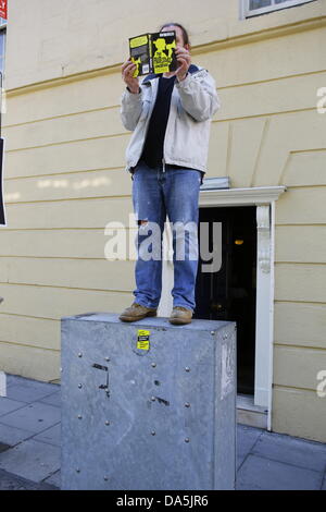 Dublino, Irlanda. 4 luglio 2013. Un manifestante sorge al di fuori del Dail sulla parte superiore di una scatola elettrica e legge "protestor's Handbook" da Bibi van der Zee. I dimostranti si fermò in silenziosa al di fuori del Dail (parlamento irlandese), la lettura di libri, per mostrare i loro sentimenti verso i banchieri e la politica di austerità al parlamento. La protesta è stata ispirata dalla permanente movimento di persone che ha dato origine a Istanbul la piazza Taksim. Credito: Michael Debets/Alamy Live News Foto Stock