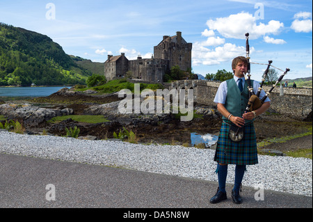 Europa Gran Bretagna, Scozia, Highlands, un lettore delle cornamuse e il Eilean Conan castello in background. Foto Stock