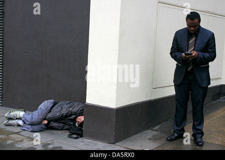 L'uomo controllando il suo telefono cellulare in prossimità di un vagabondo nel centro di Londra Foto Stock