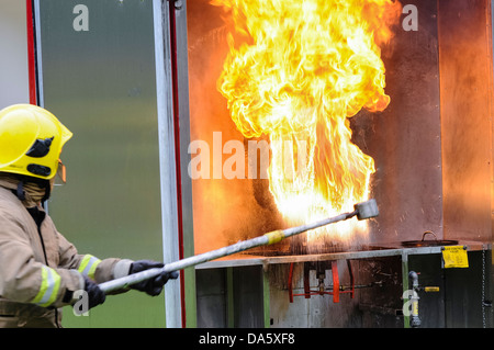 Un vigile del fuoco dimostra il risultato di versare una piccola quantità di acqua su un chip di masterizzazione pan in un ambiente controllato Foto Stock