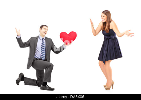 Uomo romantico dando un cuore rosso ad una giovane donna isolato su sfondo bianco Foto Stock