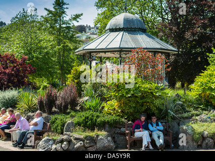 Dartmouth, Devon, Inghilterra. Il 1 luglio 2013. Royal Avenue giardini e il palco per spettacoli con persone di relax al sole. Foto Stock