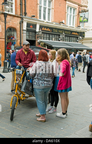 Urban Rickshaw o pedicab con autista o pilota e i clienti, Covent Garden Londra Inghilterra REGNO UNITO Foto Stock