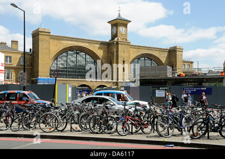 Biciclette attaccata al portabiciclette nella parte anteriore del taxi e di traffico con la stazione di King Cross dietro, London, England, Regno Unito Foto Stock
