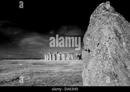 Il guarire la pietra con il resto di Stonehenge in background e dietro che Salisbury Plain al solstizio d'estate Foto Stock