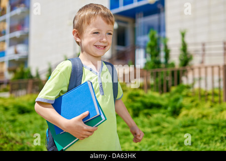 Giovane ragazzo felice con i libri di fronte all edificio scolastico Foto Stock