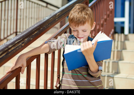 Giovane capretto felice libro sulle scale della scuola Foto Stock