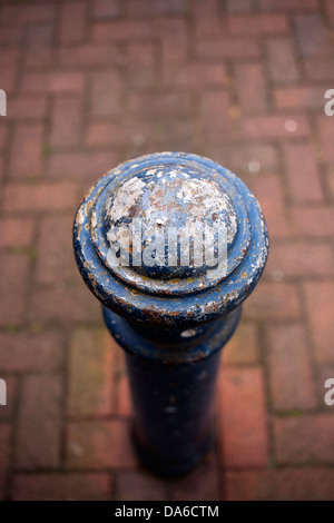 Blue weathered e ferro forgiato bollard post con testa tonda impostato in mattoni rossi fishbone pattern marciapiede Foto Stock