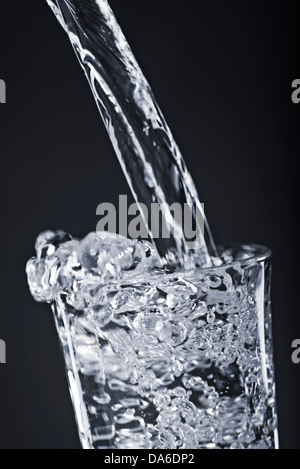 L'acqua viene versata in un bicchiere. Foto Stock