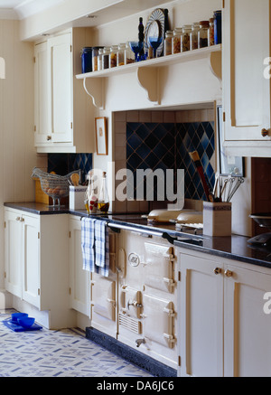 La crema Aga sotto al ripiano con fila di vetro vasetti di storage in cucina di paese Foto Stock