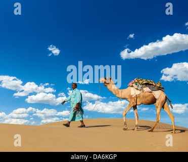 Rajasthan travel background - cameleer indiano (camel driver) con i cammelli in dune del deserto di Thar. Jaisalmer, Rajasthan, India Foto Stock