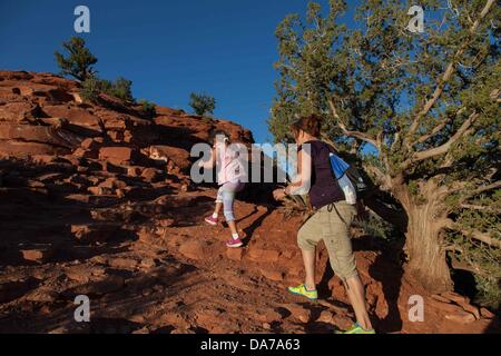 Giugno 9, 2013 - Sedona, in Arizona, Stati Uniti - Madre e figlia escursione prima del tramonto all'Aeroporto di Sedona sito vortex. Il fascino di Sedona siti Vortex. Molte persone visitare Sedona per esplorare la sua dimensione metafisica, soprattutto i suoi vortici. Pagina Bryant ha coniato il nome "vortice" nel 1980 per le aree in Sedona che sono altamente concentrato energie favorevole alla preghiera, la meditazione e la guarigione. Sedona attrazione principale è la sua schiera di pietra arenaria rossa formazioni, che sembrano glow in brillante arancio e rosso quando è illuminata dalla crescente o impostazione di sun. Le rocce rosse formano un sfondo popolare per molti o Foto Stock