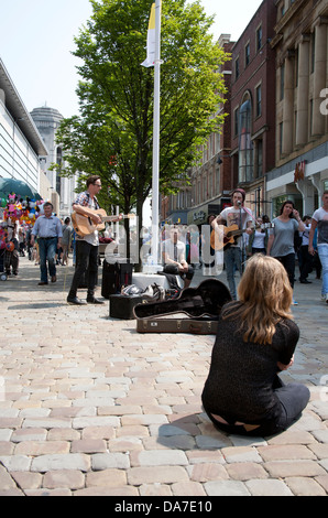 Una città di Manchester street sulla scena calda giornata di sole con acquirenti e buskers sulla strada alta. Foto Stock