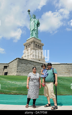 I visitatori in posa per i ritratti di famiglia di fronte alla statua della libertà su Liberty Island nel porto di New York il 4 luglio 2013. Foto Stock