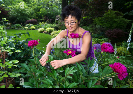 Una donna asiatica funziona su la potatura di piante nel suo bellissimo giardino Foto Stock