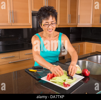 Donna asiatica nella sua cucina disponendo frutto per un piatto di frutta Foto Stock