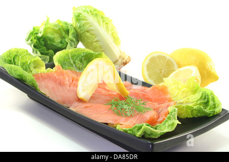 Fette di Salmone con limone e aneto su insalata verde Foto Stock